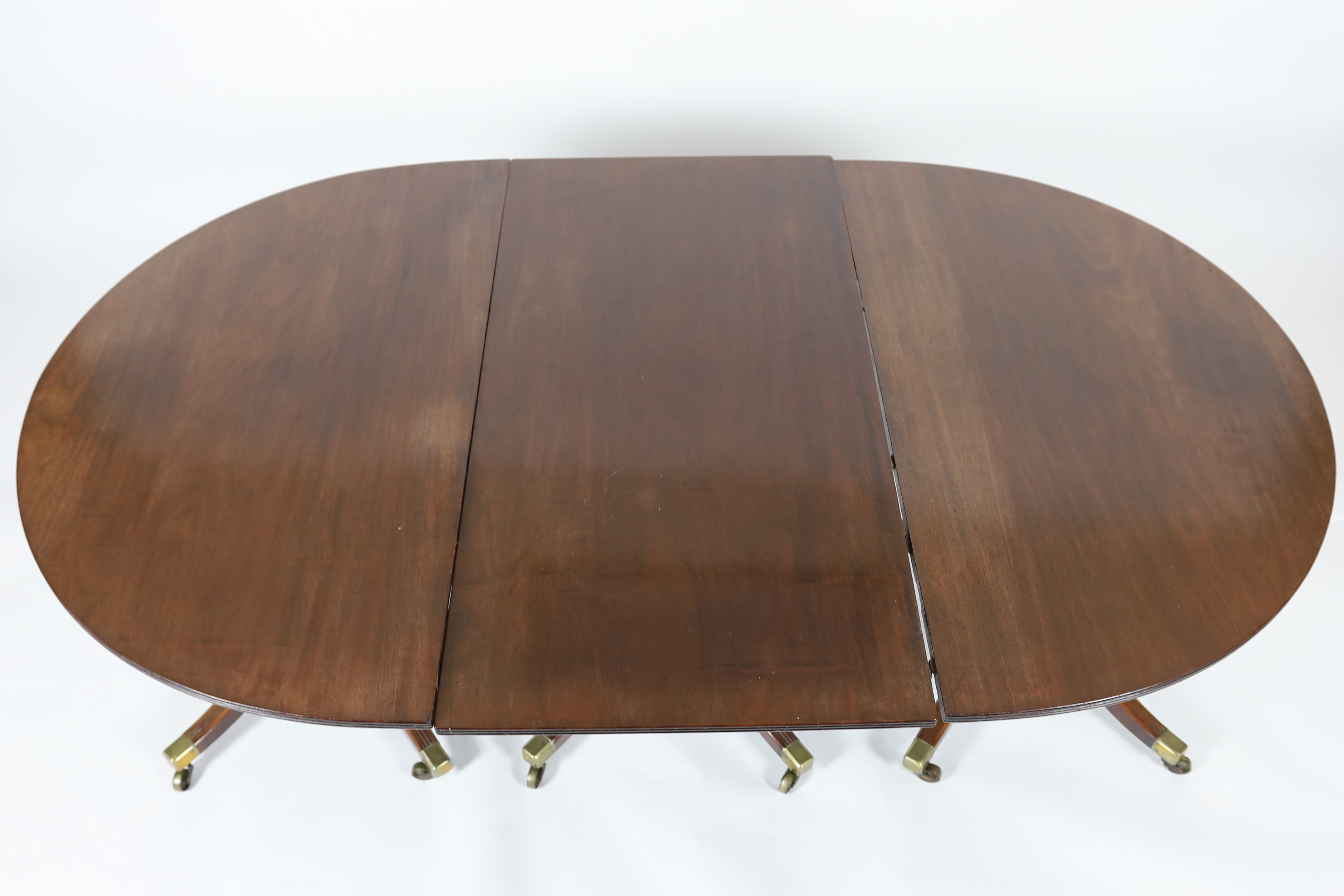 A George III style mahogany triple pillar D end extending dining table in the manner of Gillows